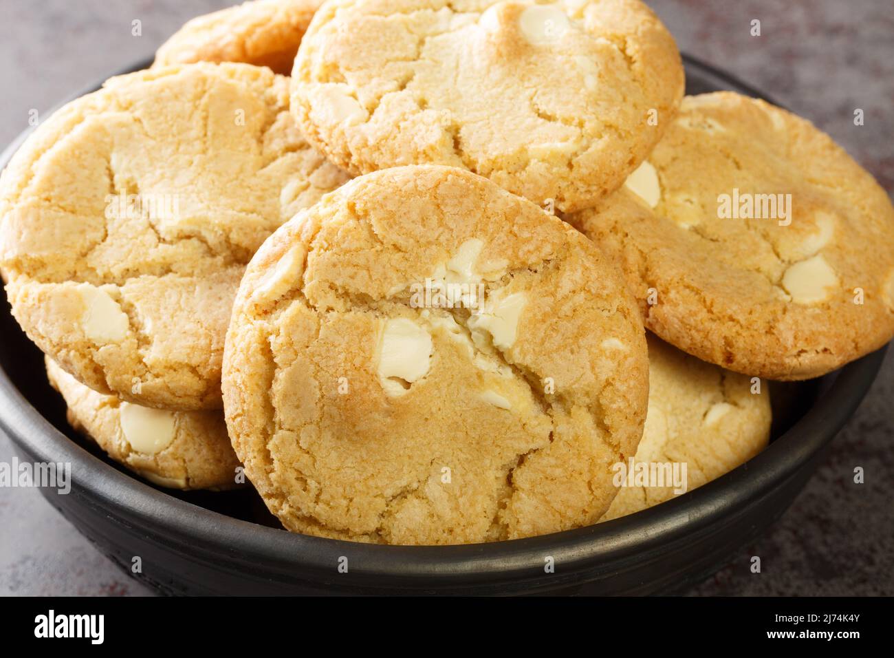mucchio di gocce di cioccolato bianco e biscotti di noci di macadamia sul primo piano del tavolo. Orizzontale Foto Stock