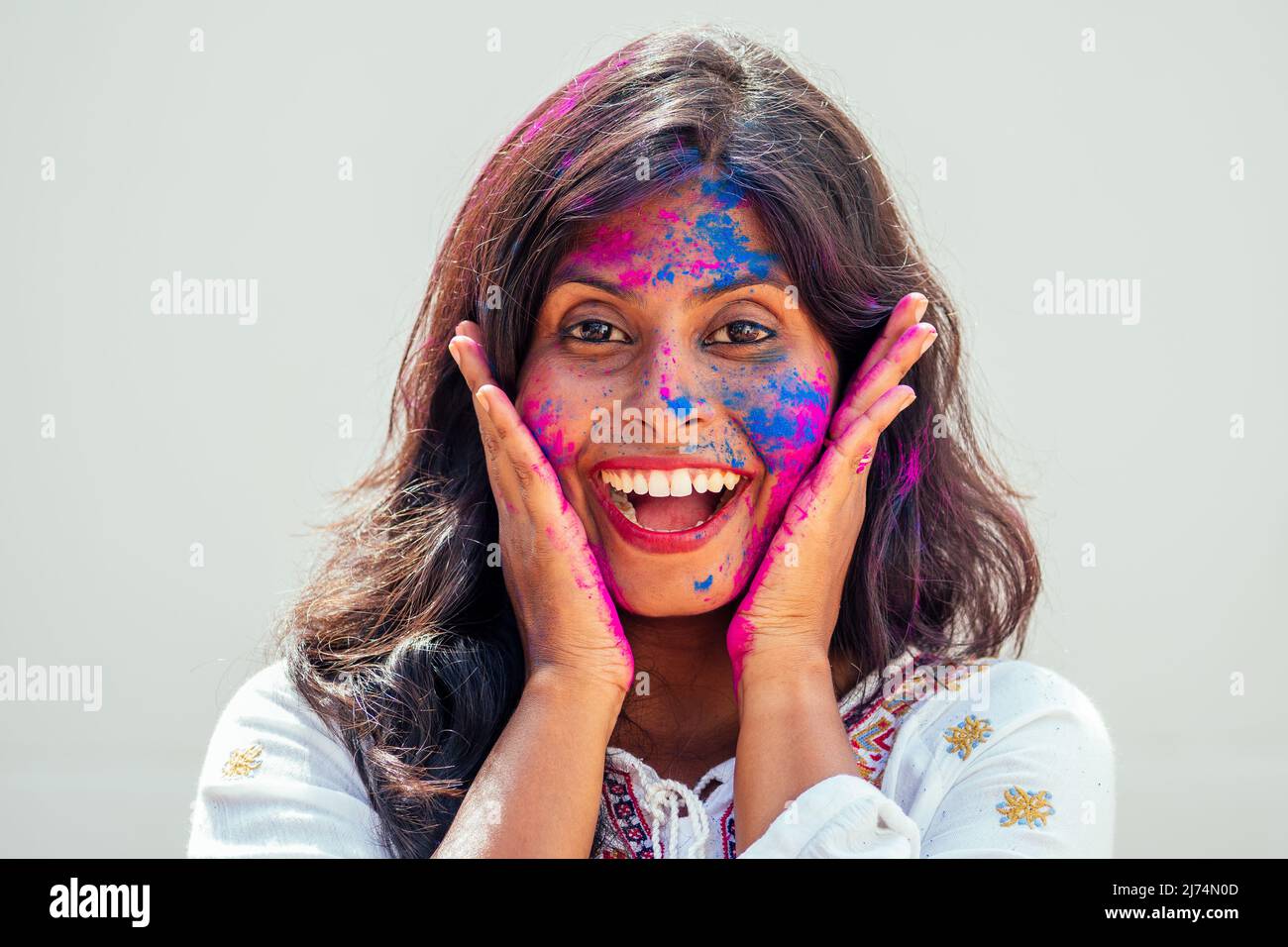 Holi Festival dei colori. Ritratto di ragazza indiana felice in holi colore. Lei ballare e divertirsi a parete bianca studio sfondo Foto Stock