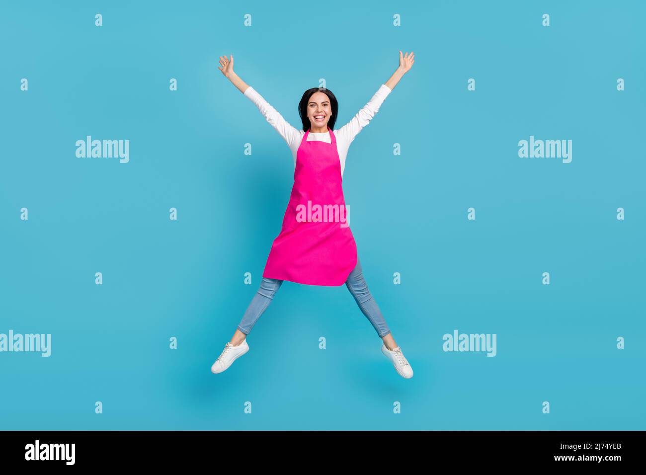 La dimensione del corpo a tutta lunghezza vista di attraente ragazza cheery specialista jumping avendo divertimento isolato su sfondo di colore blu brillante Foto Stock