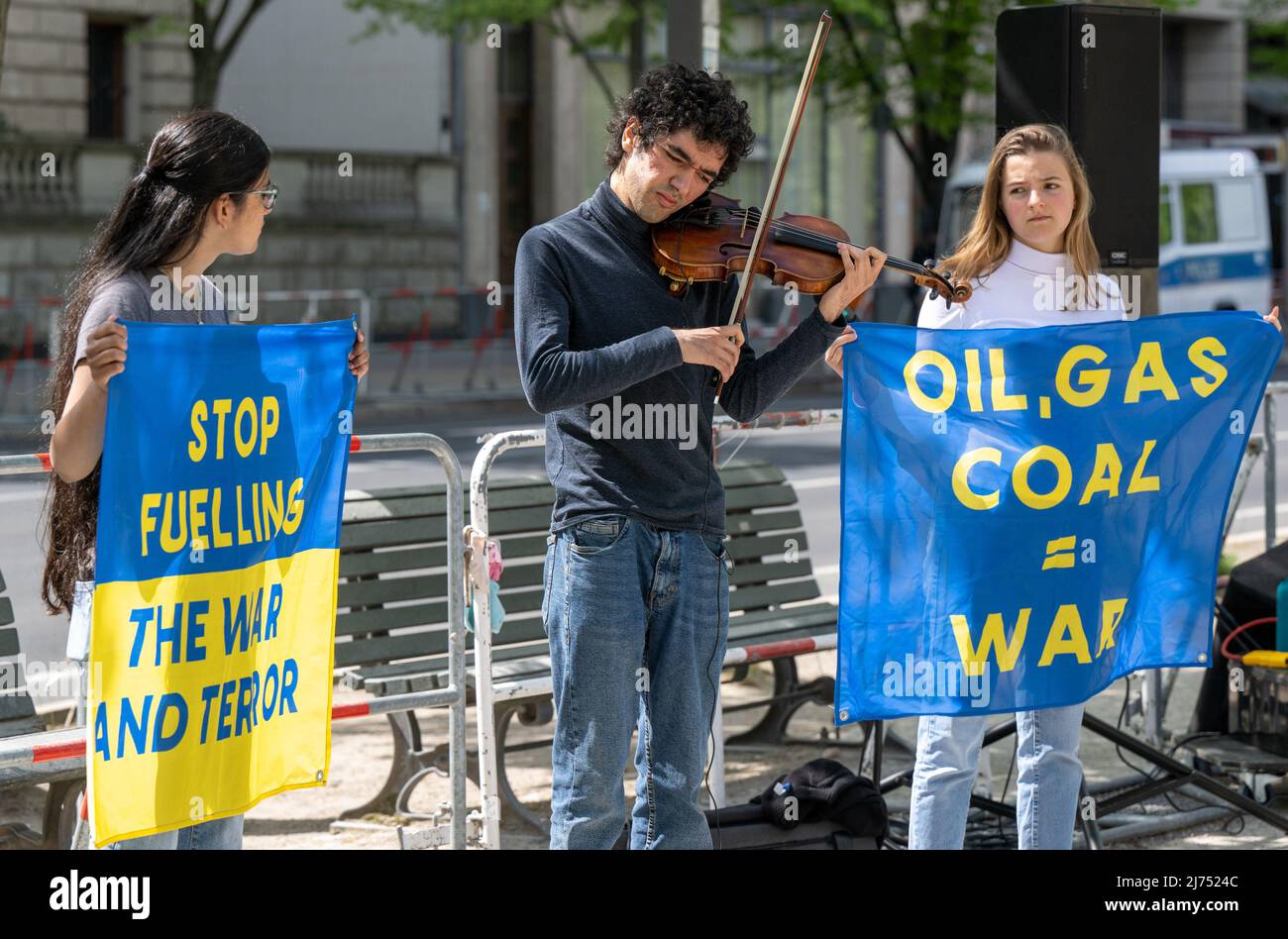 06 maggio 2022, Berlino: Arshak Makichyan (M), attivista ambientale e violinista russo, suona il suo violino di fronte all'Ambasciata russa mentre due giovani attivisti ambientali accanto a lui hanno striscioni che leggono 'petrolio, gas, carbone = Guerra' e 'Stop FUfetting the War and Terror'. Il venerdì per il futuro attivista, fuggito dalla Russia, sta protestando contro la guerra in Ucraina con la sua azione. Foto: Monika Skolimowska/dpa Foto Stock