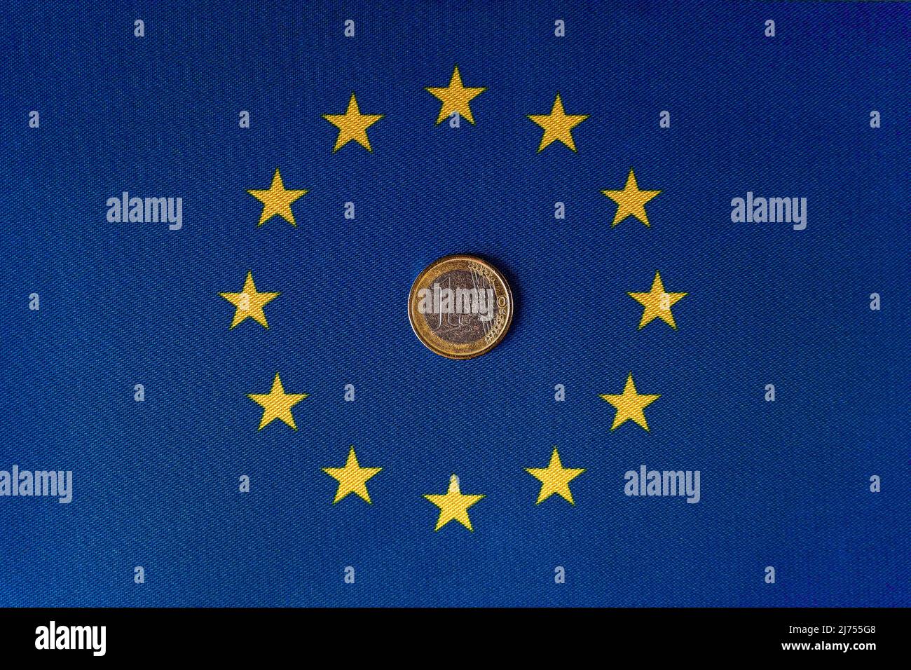 Una moneta da euro al centro della bandiera dell'UE. Foto Stock
