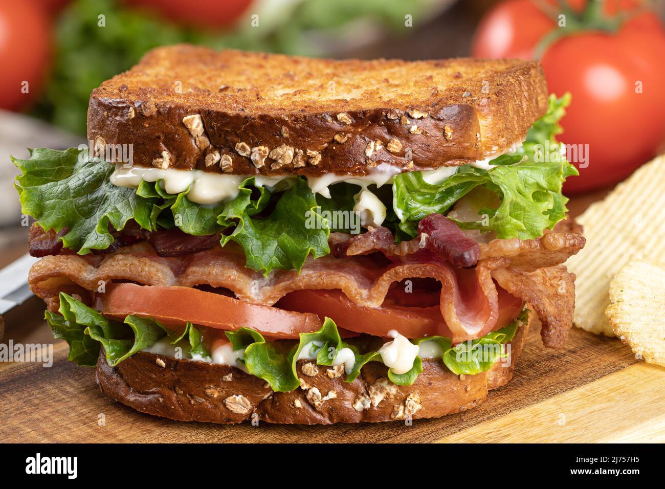 Primo piano di panino blt fatto con pancetta, lattuga e pomodoro su pane tostato intero grano su un tagliere di legno Foto Stock