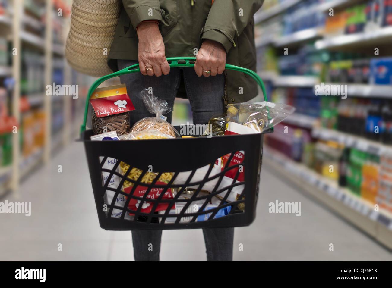 Donna che acquista al supermercato, lei sta trasportando il carrello pieno di shopping, primo piano. Foto Stock
