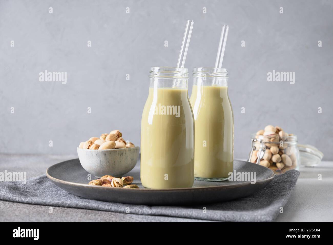 Pistacchio in vetro su sfondo grigio. Orientamento orizzontale. Bevanda vegetale alternativa vegana. Foto Stock