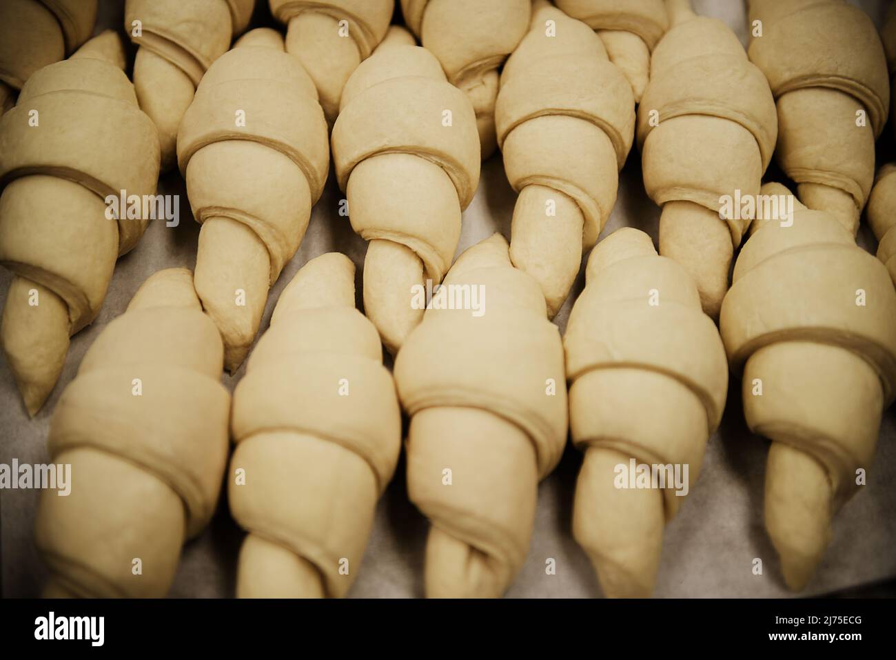 croissant seduti su una padella in attesa di essere messi in forno in una panetteria Foto Stock