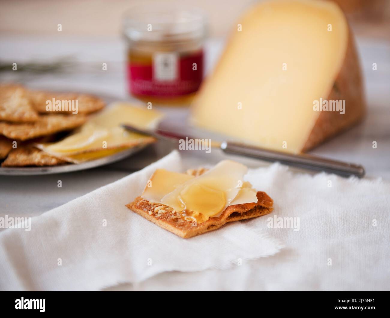 Formaggio affettato su un cracker con miele di tartufo Foto Stock