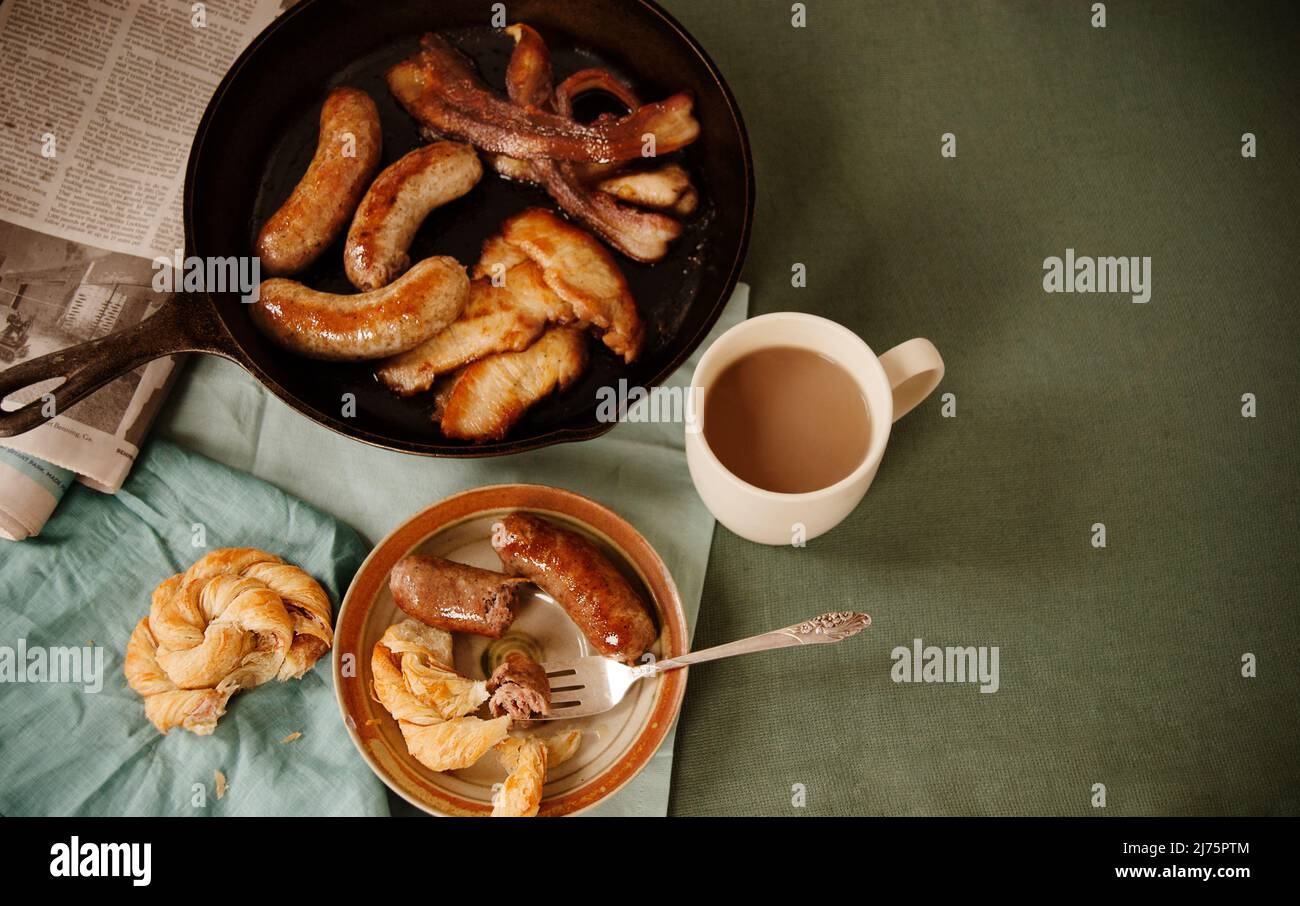 Colazione a base di salsiccia, pancetta, caffè e croissant Foto Stock