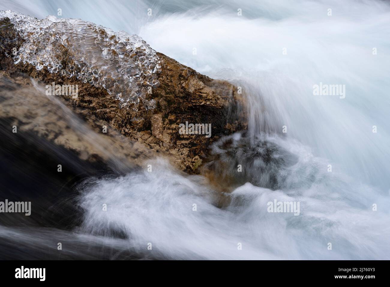Ghiaccio limpido in inverno su una pietra nella corrente al Rissbach nella cosiddetta Eng in Tirolo nelle montagne del Karwendel con acqua limpida e forte corrente Foto Stock