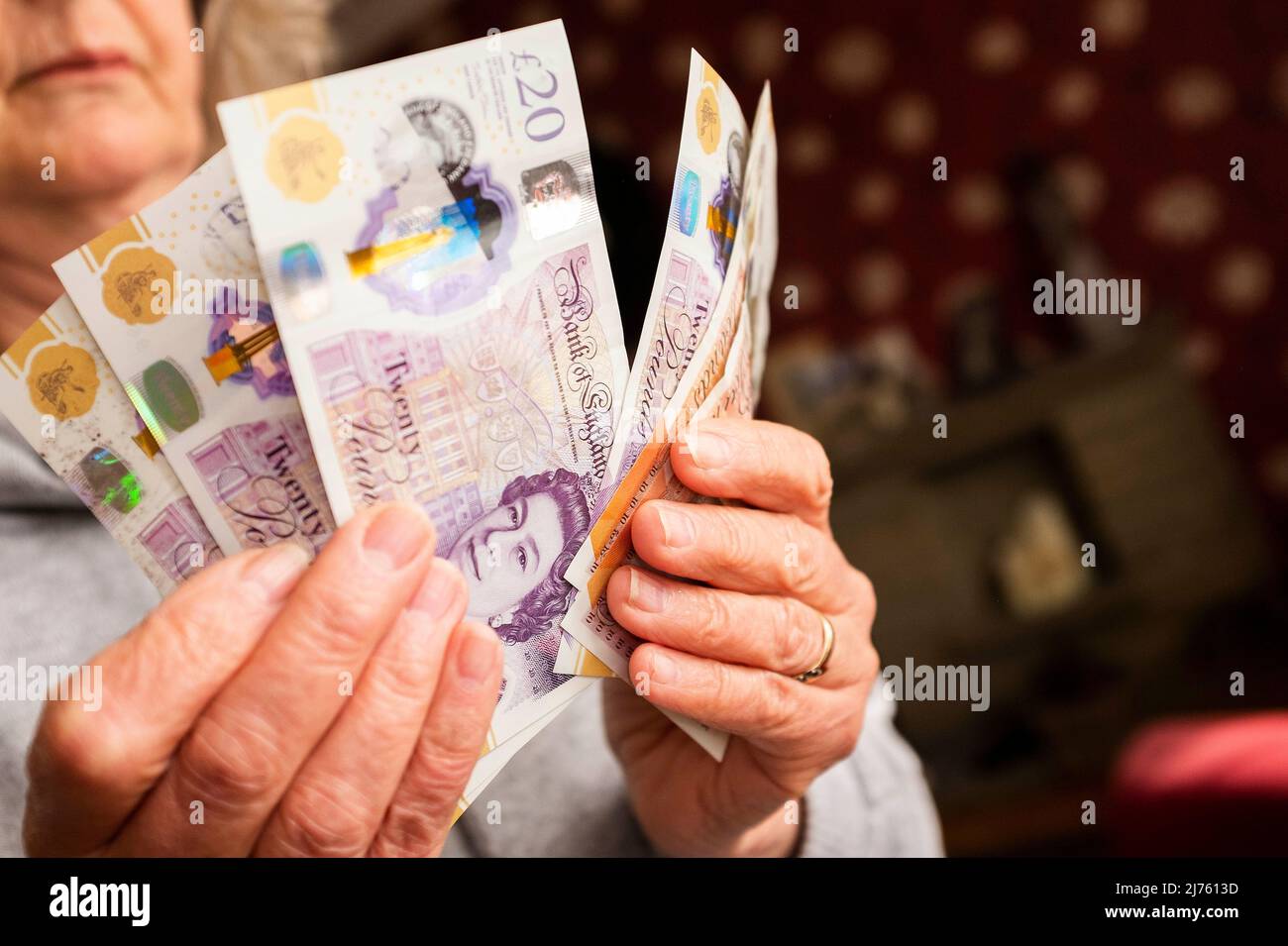 Mani in possesso di banconote £20 e £10 per illustrare i contanti in mano e pagare in contanti durante la crisi economica nel Regno Unito Foto Stock