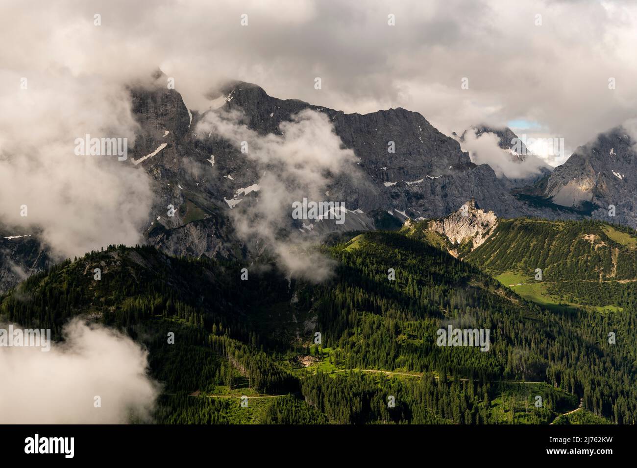 La Rappenklammspitze nella Valle del Rodano nel Karwendel vicino Hinterriss nelle Alpi tirolesi brilla nella luce del pomeriggio, mentre dense nubi basse si raccolgono e le alte pareti della catena del Karwendel settentrionale si innalzano sullo sfondo. Foto Stock