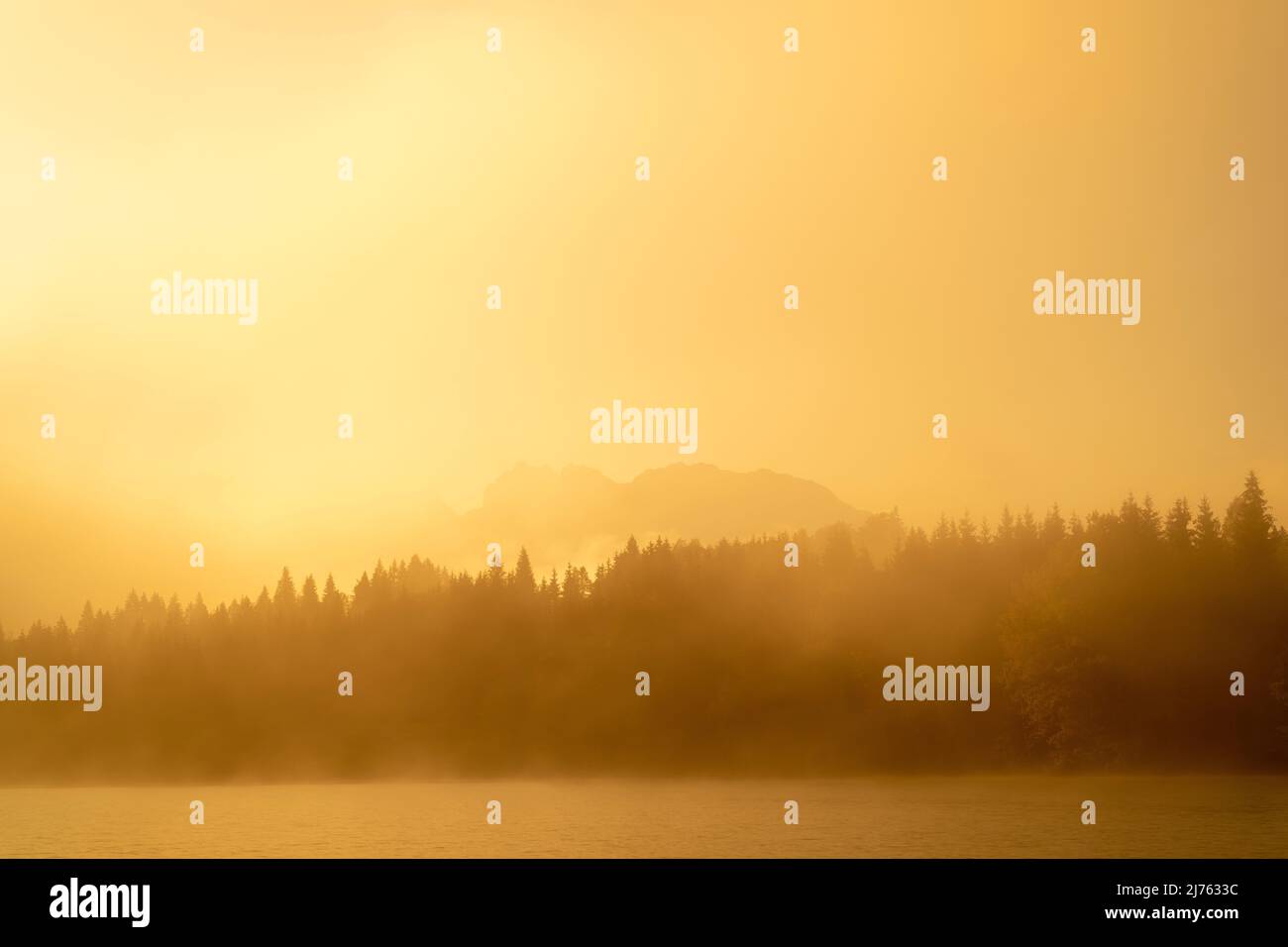 Il Geroldsee, anche Wagenbrüchsee in una mattinata di inizio autunno. La luce dell'alba colora tutto l'arancio dorato, sullo sfondo si vede l'ombra del Karwendel. Foto Stock