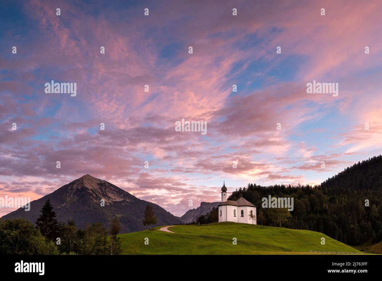 Il piccolo Annakircherl, una piccola cappella su una collina in Achenkirch alla fine del Karwendel nelle Alpi, Tirolo dopo il tramonto. I toni viola e blu dominano il cielo della sera. Sullo sfondo le montagne. Foto Stock