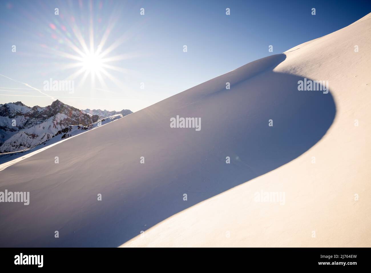 Sole invernale sulle Pleisenspitze e sul Karwendel, in primo piano una nevicata, sotto forma di una duna con ombra nella cava. Foto Stock