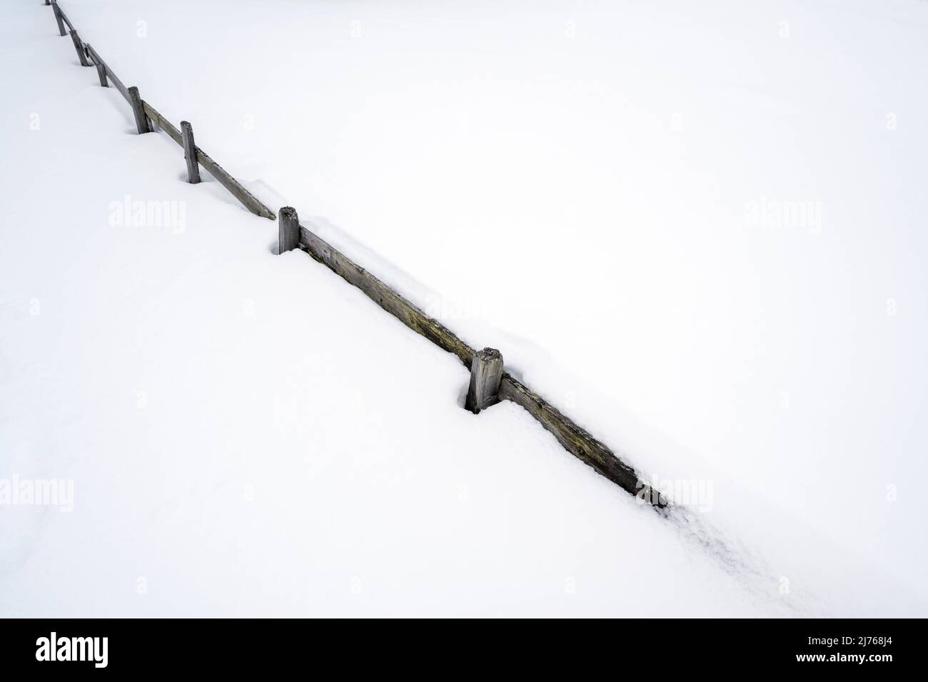 Una recinzione in legno, profonda nella neve. Solo le doghe più in alto ancora sbirciano. Foto Stock