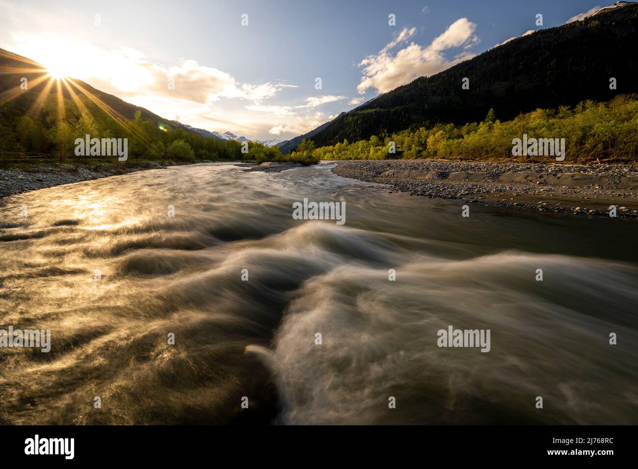 Tramonto con stella del sole all'Isel, un fiume selvaggio nel Tirolo orientale vicino a Lienz, con rapide all'acqua corrente. Foto Stock Tramonto con stella del sole all'Isel, un fiume selvaggio nel Tirolo orientale vicino a Lienz, con rapide all'acqua corrente. Foto Stock