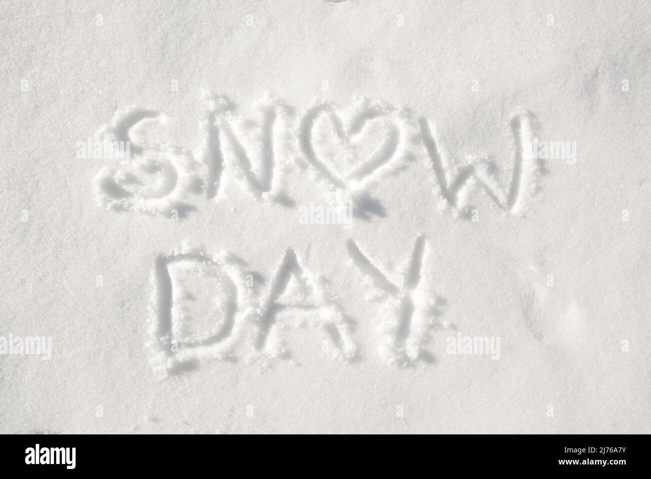 Testo 'giorno di neve' scritto nella neve, con un cuore per la lettera o; concetto di una giornata felice a causa del tempo nevoso Foto Stock