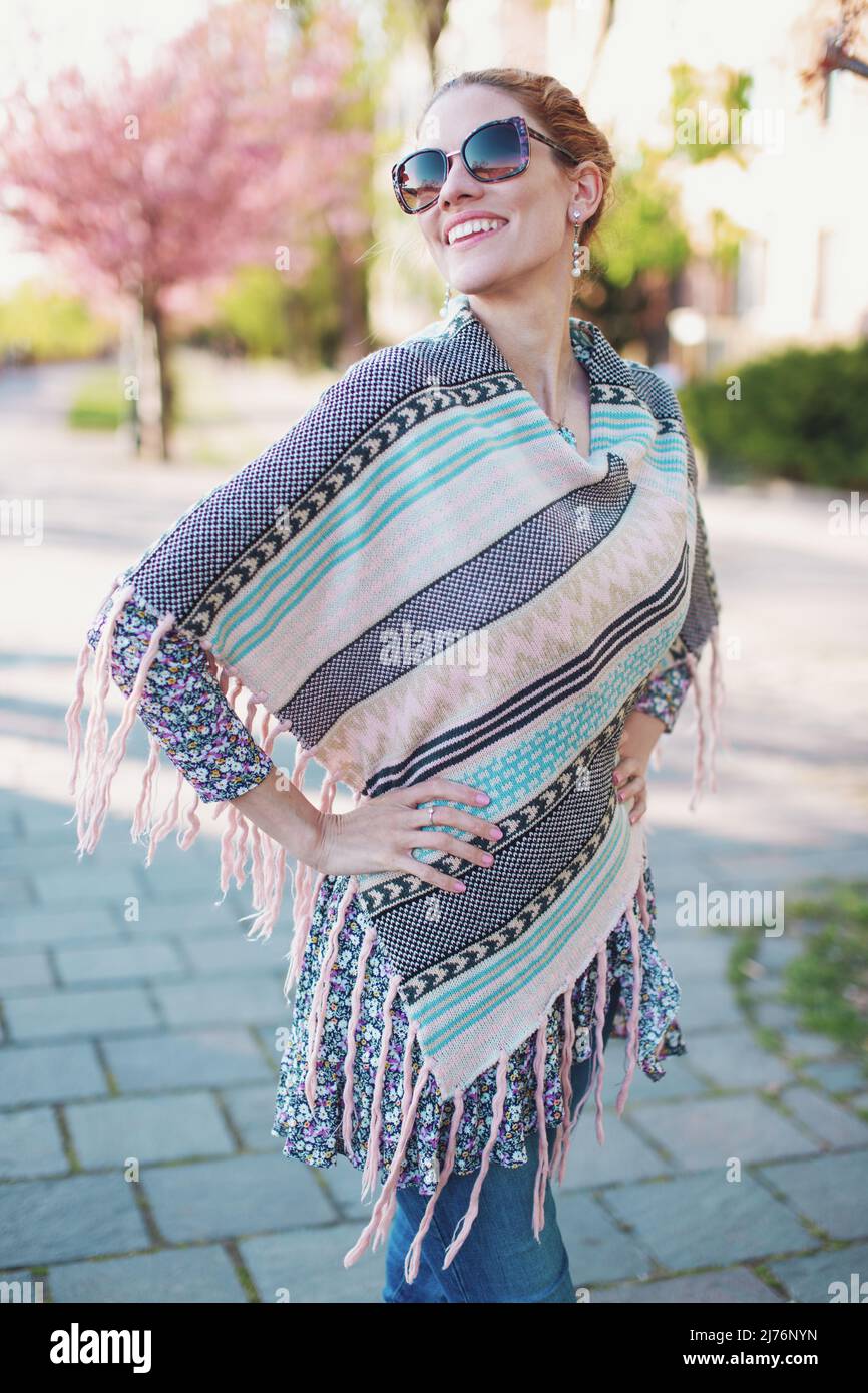 Felice giovane allegro hipster 30s donna in poncho Toothy sorriso nel parco Foto Stock