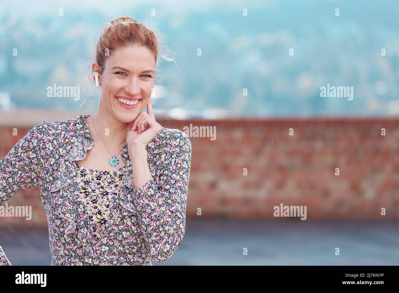 Felice giovane donna rossa con dispositivo a mani libere toothy sorridente, spazio vuoto Foto Stock