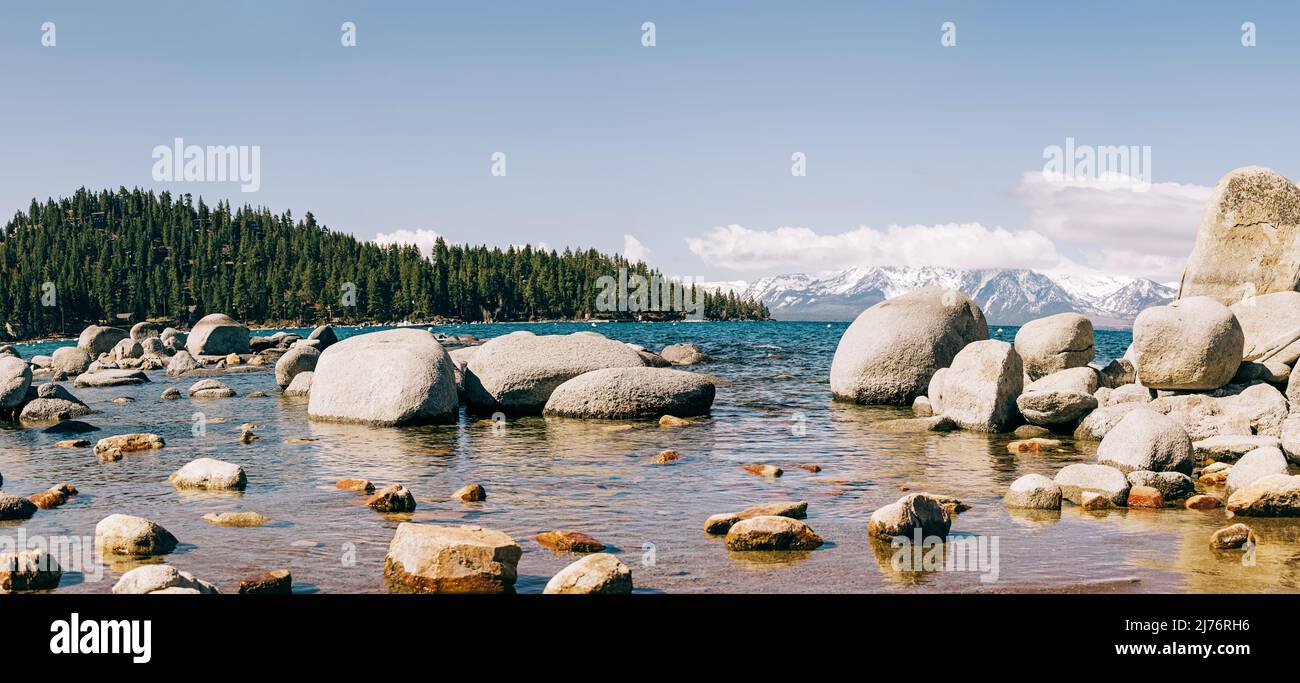 Panorama della spiaggia di Zephyr Cove sul lago Tahoe. Pietre in acqua e montagne innevate sullo sfondo Foto Stock