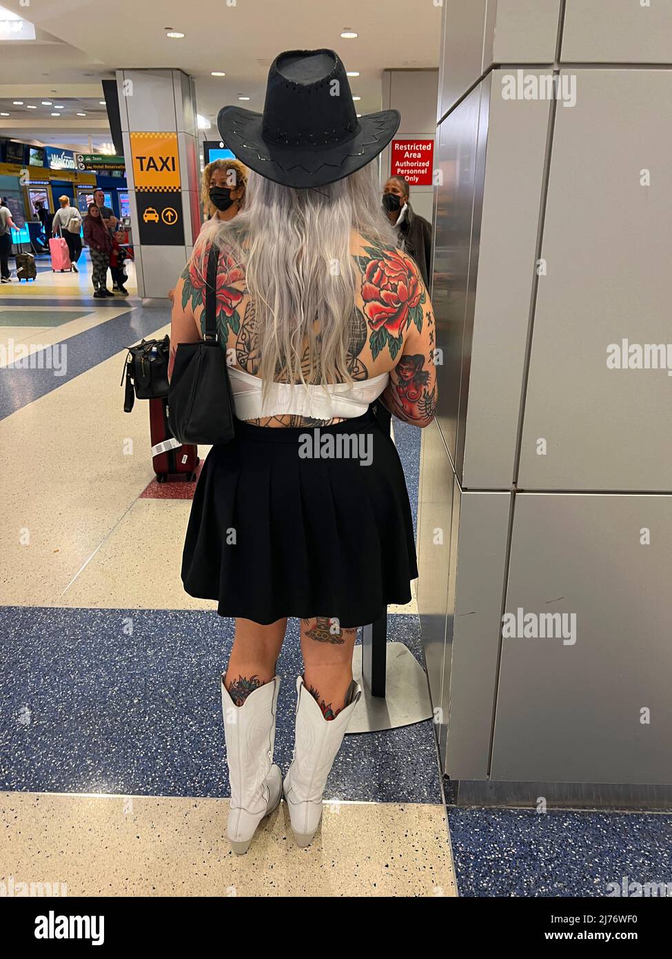 Donna che mostra l'arte del tatuaggio di alta qualità sul suo corpo aspetta un amico che vola nel termainal internazionale all'aeroporto JFK a New York City. Foto Stock