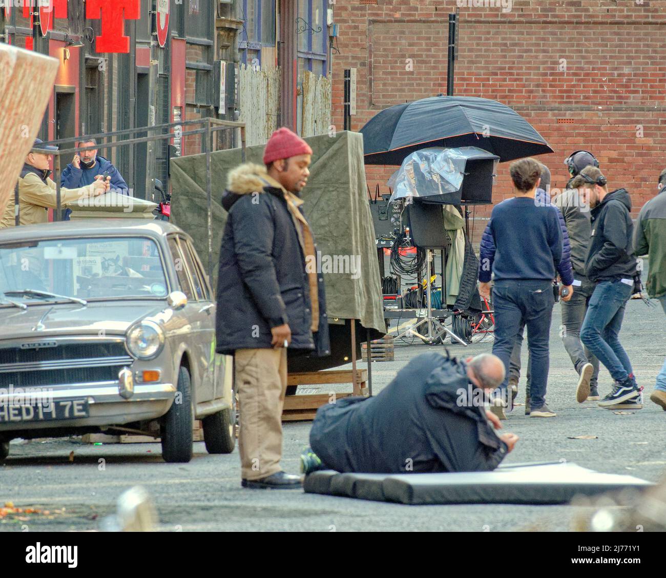 Glasgow, Scozia, Regno Unito 6th maggio 2022. Parnie Street famosa come il contesto principale nel nuovo film batgirl è andato da gotham a londra 1970s per il film Borderland un thriller ira dalla magia dei film. AML Ameen e Sophia Brown in una scena in cui si trovano in un negozio che sta dipingendo e viene girato da un cecchino dopo aver lasciato i locali che si vede tenere è testa e urla per aiuto come il suo corpo è nel mezzo della strada. Credit Gerard Ferry/Alamy Live News Foto Stock