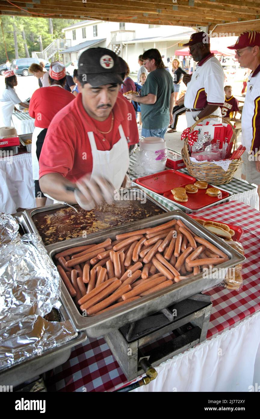 Faccia di Fast food ispanico cuoco bollente e fare hot dog, whinnies per picnic banchetto per famiglie etniche bambini Foto Stock