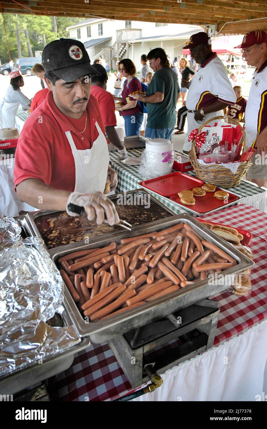 Faccia di Fast food ispanico cuoco bollente e fare hot dog, whinnies per picnic banchetto per famiglie etniche bambini Foto Stock