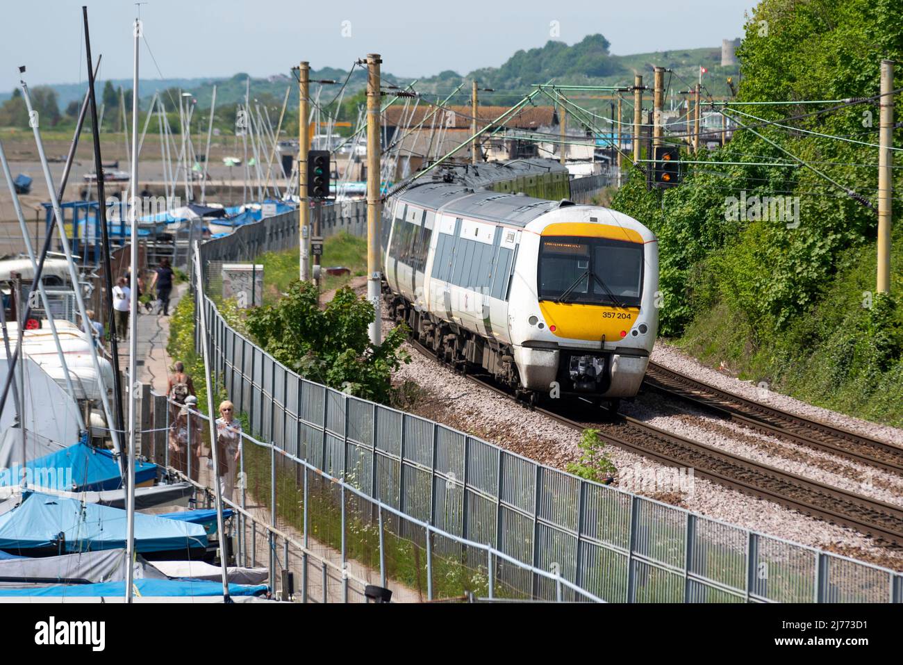 C2C treno che passa a piedi su un sentiero vicino a Leigh on Sea, Southend on Sea, Essex, Regno Unito. Londra elettrificata Southend Railway gestita da Trenitalia UK Foto Stock