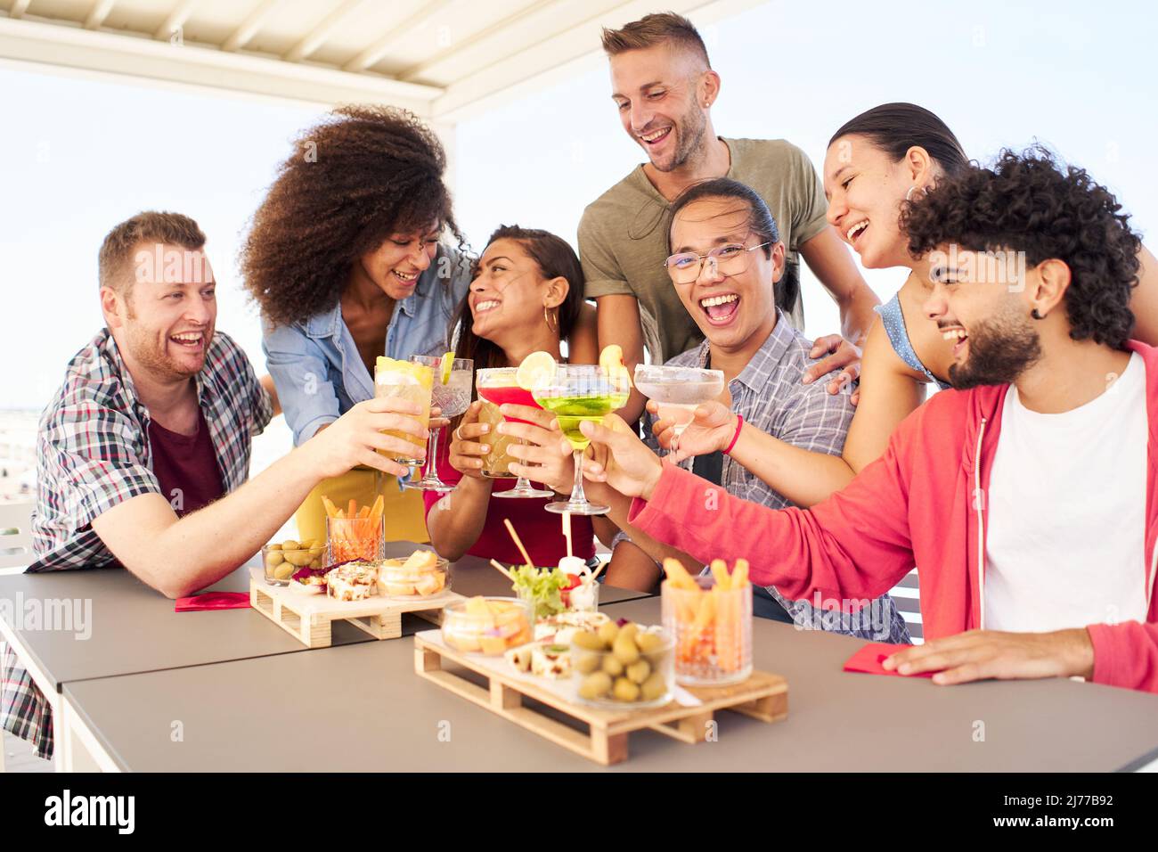 Multirazziale giovani che tengono cocktail bevande. Amici che si divertono insieme, tostando cocktail sul tetto. Concetto di stile di vita sociale di riunione Foto Stock