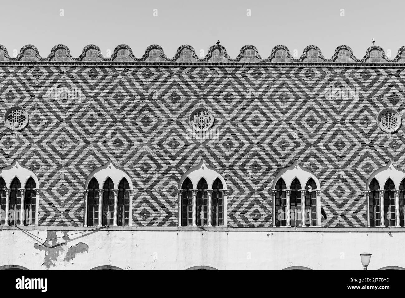 Finestre antiche in legno bianco e nero con balkoni allungati su una vecchia parete dipinta. Foto Stock