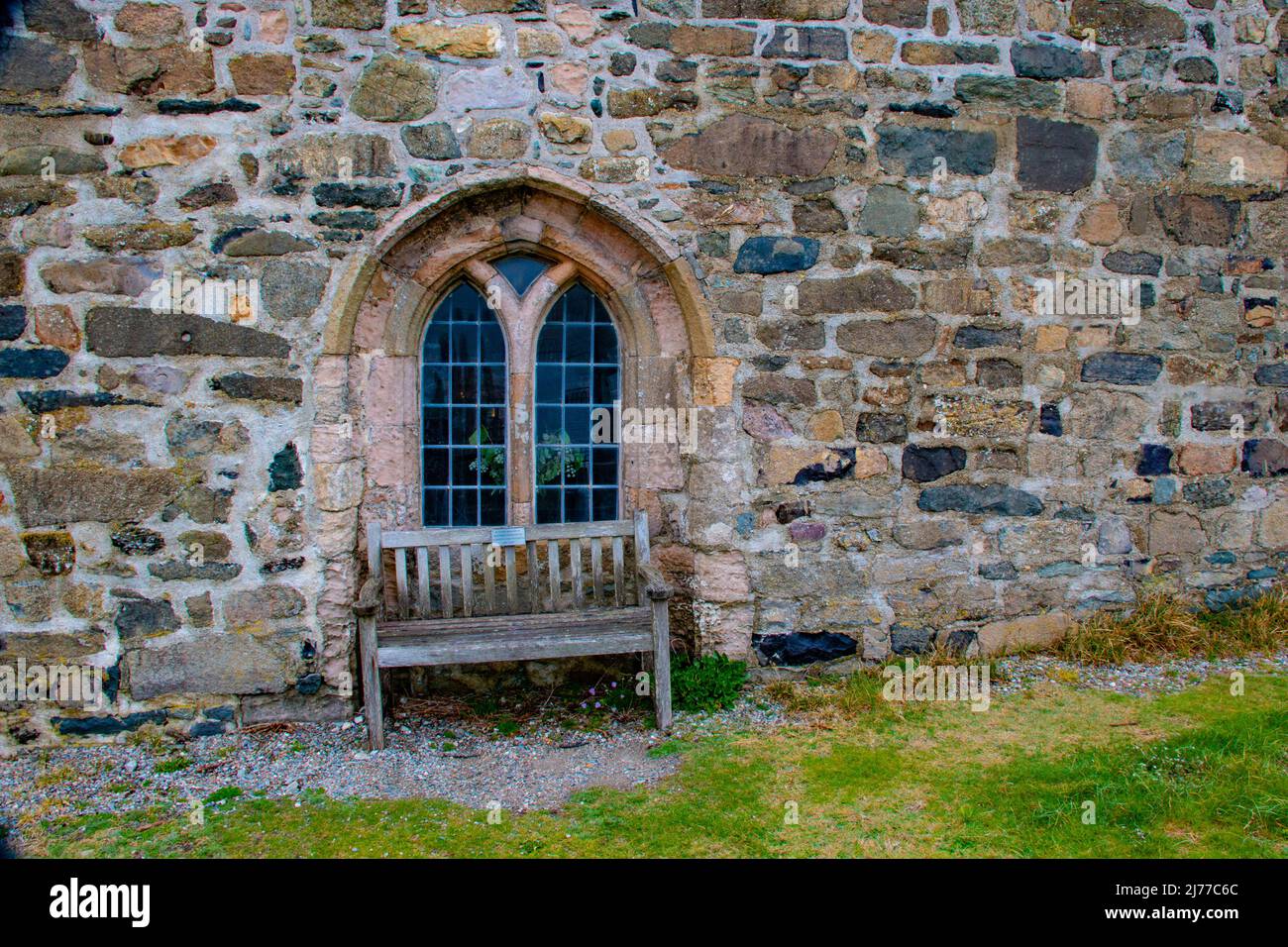 Tranquillo cimitero con antica finestra normanna, Chiesa di St Hywyn, Aberdaron nr Pwllheli, Gwynned, Galles del Nord Foto Stock