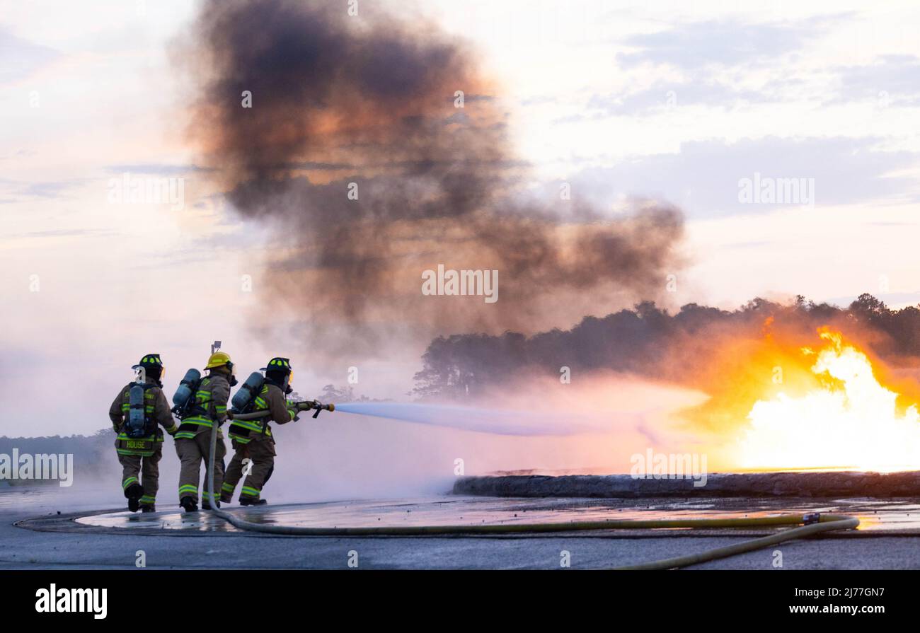 Marines USA con aerei, salvataggio e estinzione incendi (ARFF), quartier generale e quartier generale Squadron, utilizzare un team di tre uomini per mettere in sicurezza un incendio controllato sulla Marine Corps Air Station (MCAS) Cherry Point, North Carolina, 4 maggio 2022. GLI MCA Cherry Point Marines e il personale dell'aeroporto regionale della Carolina del litorale conducono questo esercizio congiunto per migliorare l'efficienza dei loro vigili del fuoco, costruire la coesione interagenzia e condividere conoscenza ed esperienza. (STATI UNITI Foto del corpo marino di Lance CPL. Jade Farrington) Foto Stock