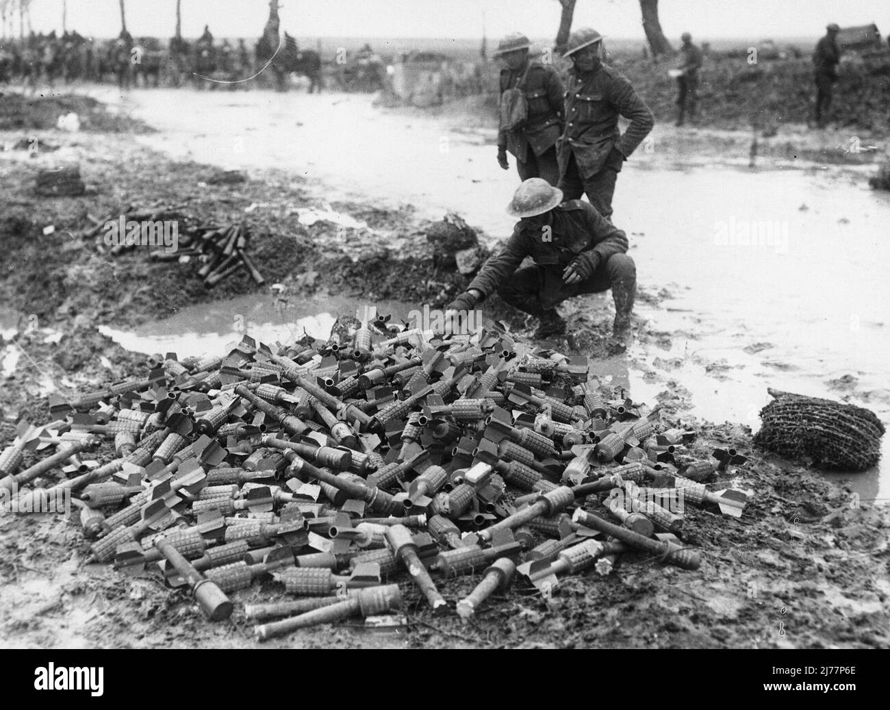 Un soldato che ispeziona catturò armi tedesche, Francia. Sullo sfondo è visibile il campo fangoso insieme a pistole trainate da cavalli e paraschioni di alberi. Questi sono siluri Ariel o ciò che il soldato chiama mele di pino Foto Stock
