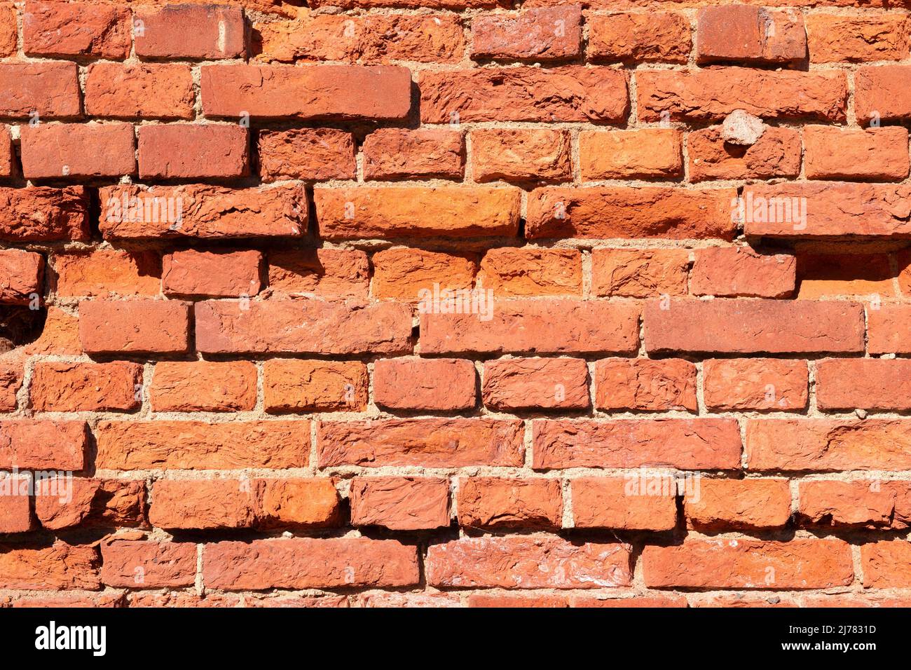 Un frammento di un vecchio muro di mattoni rossi in una giornata di sole Foto Stock
