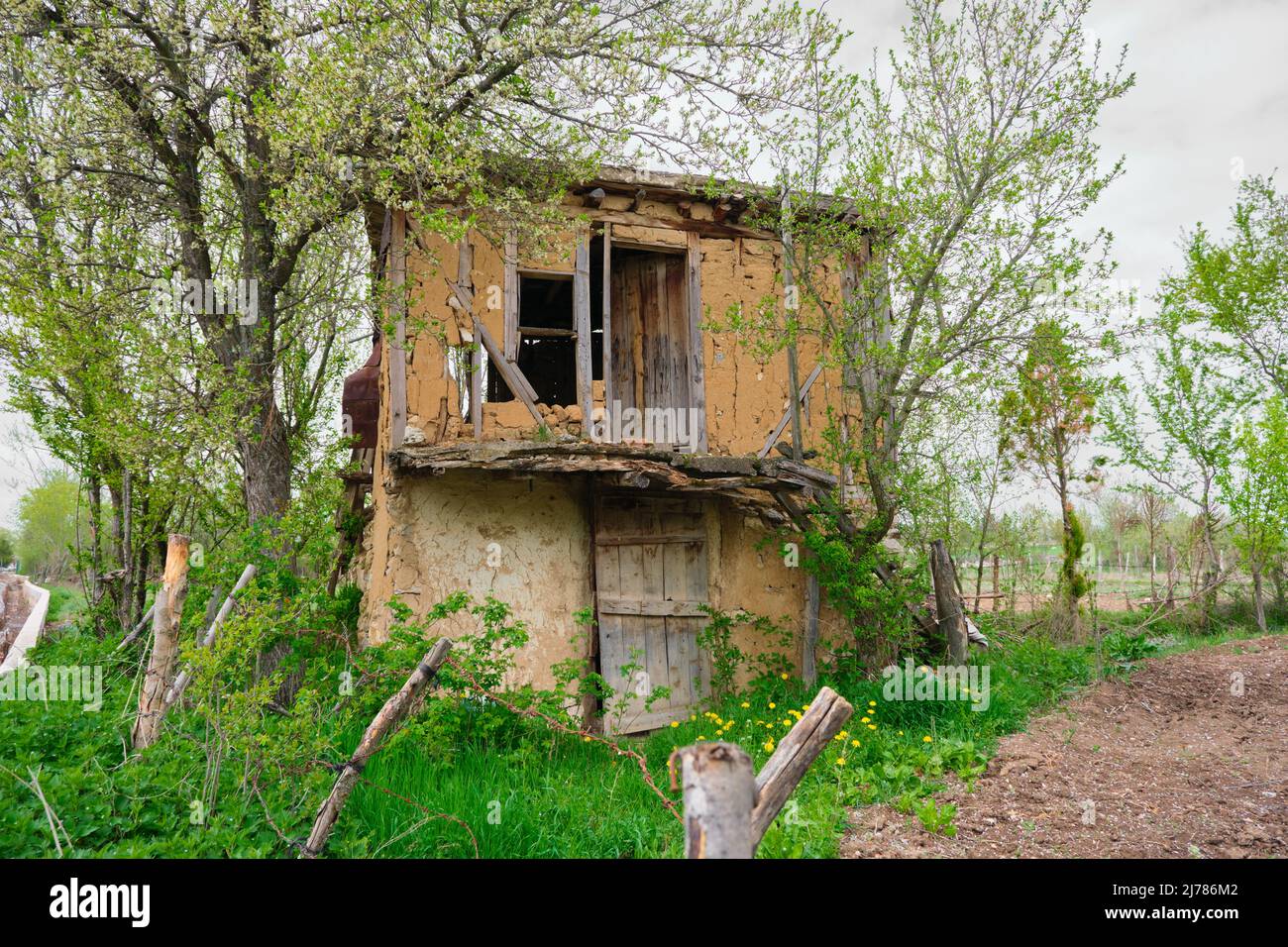 Casa antica e di campo marrone, casa abbandonata di fango e legno, casa abbandonata dietro gli alberi. Foto Stock