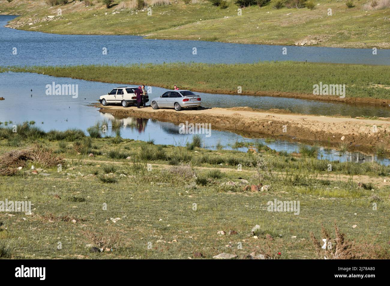 04.05.2022. Manisa. Turchia. La gente parcheggia molto vicino al lago con auto vecchie. Persone e auto riflessione sull'acqua. Foto Stock