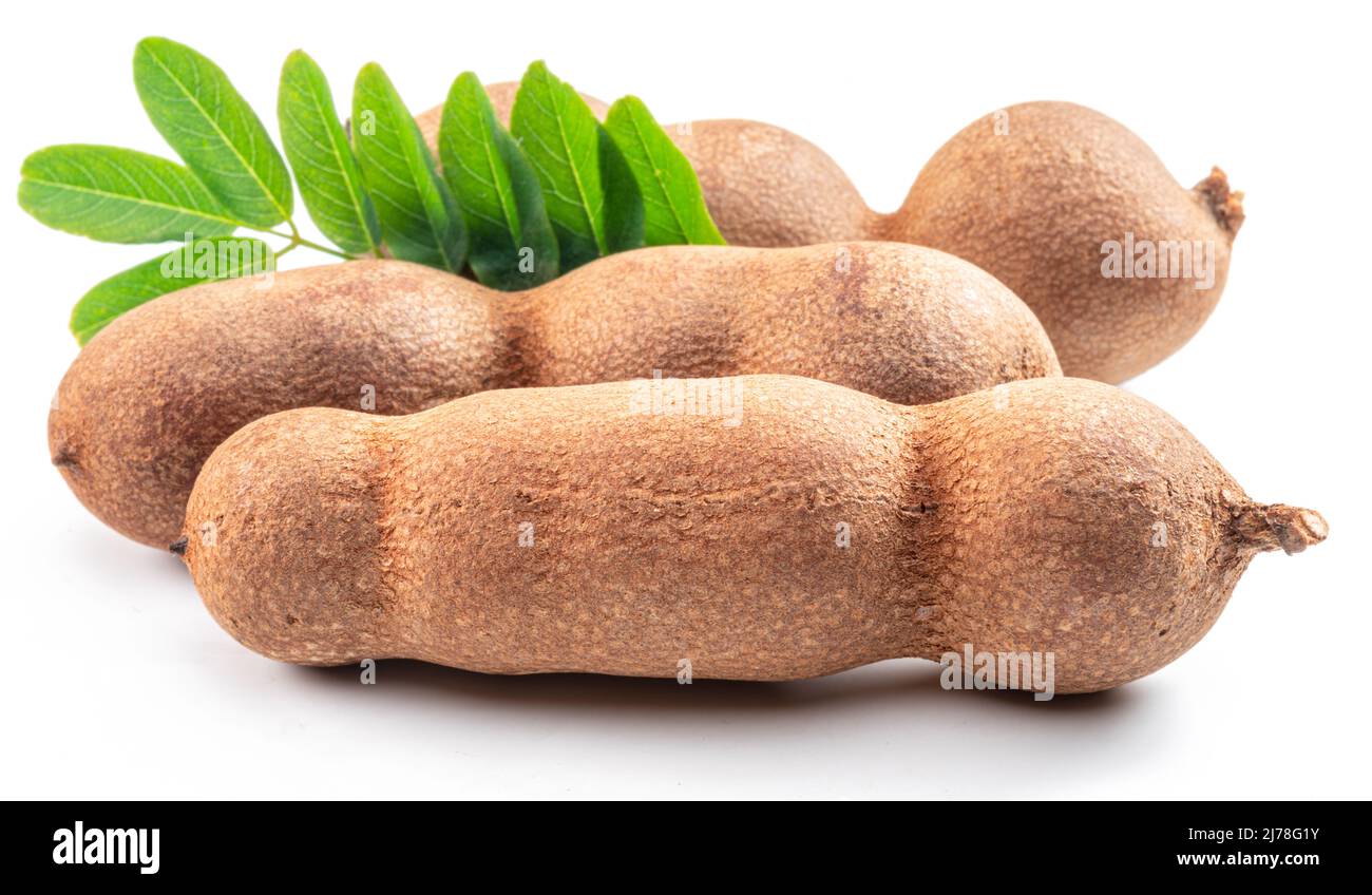 Cialde di frutta e foglie mature di tamarindo isolate su sfondo bianco. Foto Stock