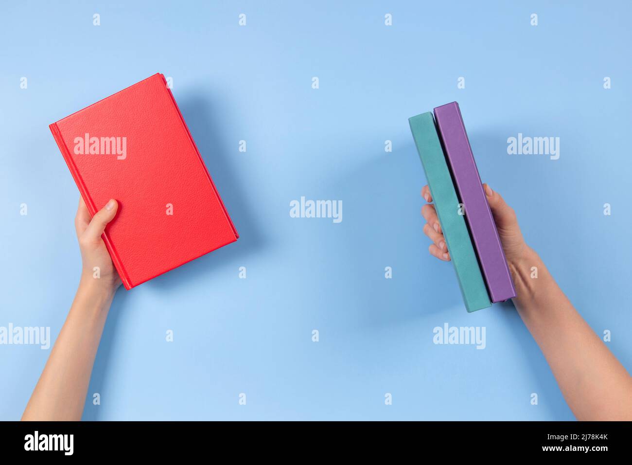 Mani che tengono i libri su sfondo blu chiaro. Istruzione, autoapprendimento, scambio di libri, condivisione, concetto di bookcrossing Foto Stock