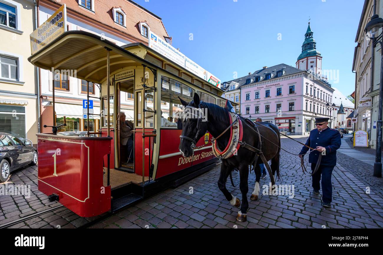 07 maggio 2022, Sassonia, Döbeln: Il coachman imbratta il cavallo del tram trainato da cavalli al capolinea del municipio. Con una potenza di 1 cv, i passeggeri viaggiano su binari lungo l'abbondante percorso di un chilometro. A Döbeln, il tram trainato da cavalli è presto in funzione fino alla Chiesa di Nicolai. Il denaro per l'estensione della linea proviene dai beni della RDT dei partiti e delle organizzazioni di massa. Foto: Matthias Rietschel/dpa/ZB Foto Stock