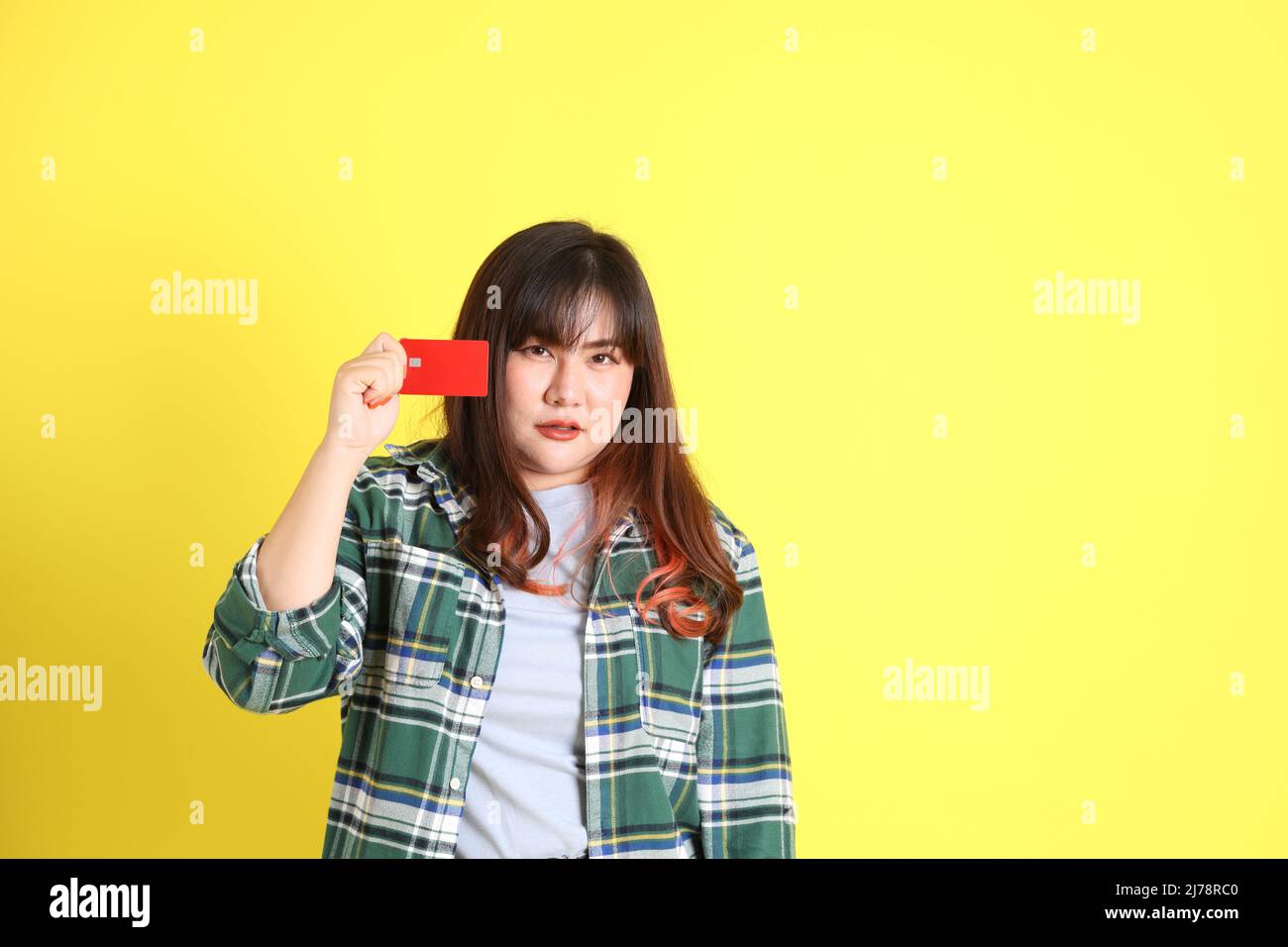 La donna asiatica chubby in piedi sullo sfondo giallo con i vestiti casual. Foto Stock