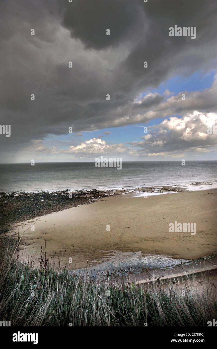 spiaggia tempestosa con due lontane figuresat bassa marea ovest runton nord norfolk inghilterra Foto Stock