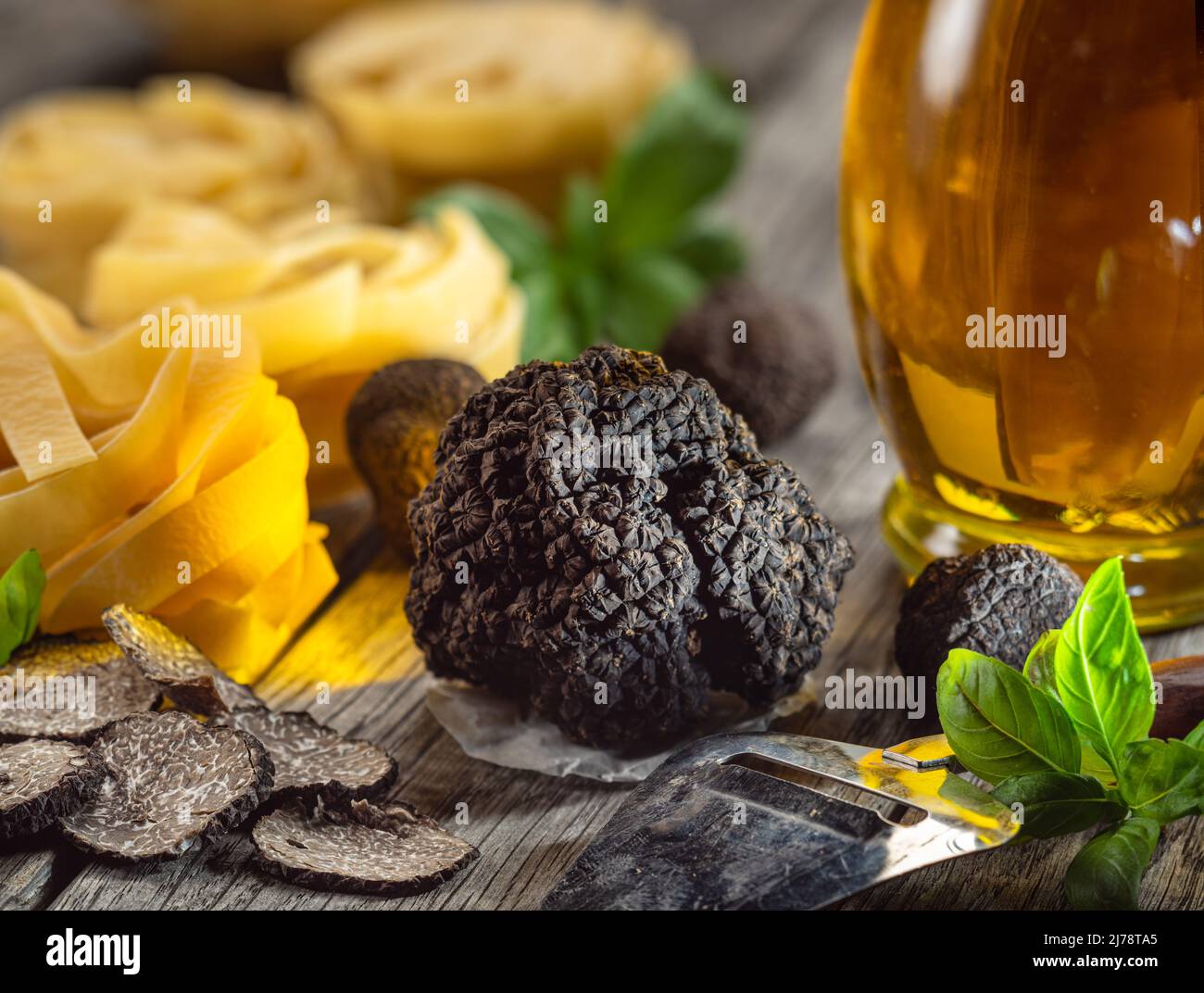 Tartufo invernale commestibile nero, tagliatelle e basilico fresco su tavola di legno. Gli ingredienti di cottura più popolari. Foto Stock