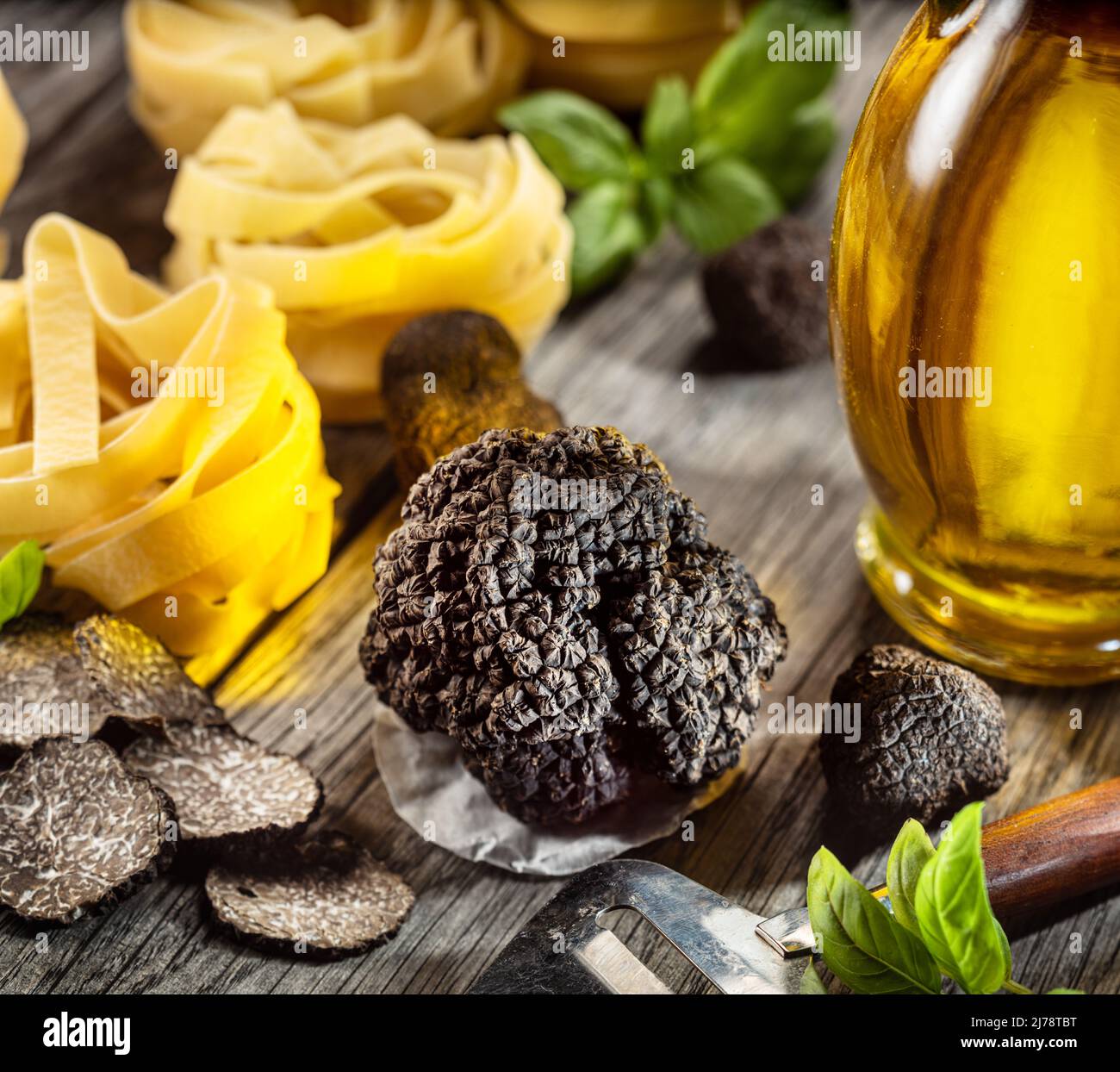 Tartufo invernale commestibile nero, tagliatelle e basilico fresco su tavola di legno. Gli ingredienti di cottura più popolari. Foto Stock
