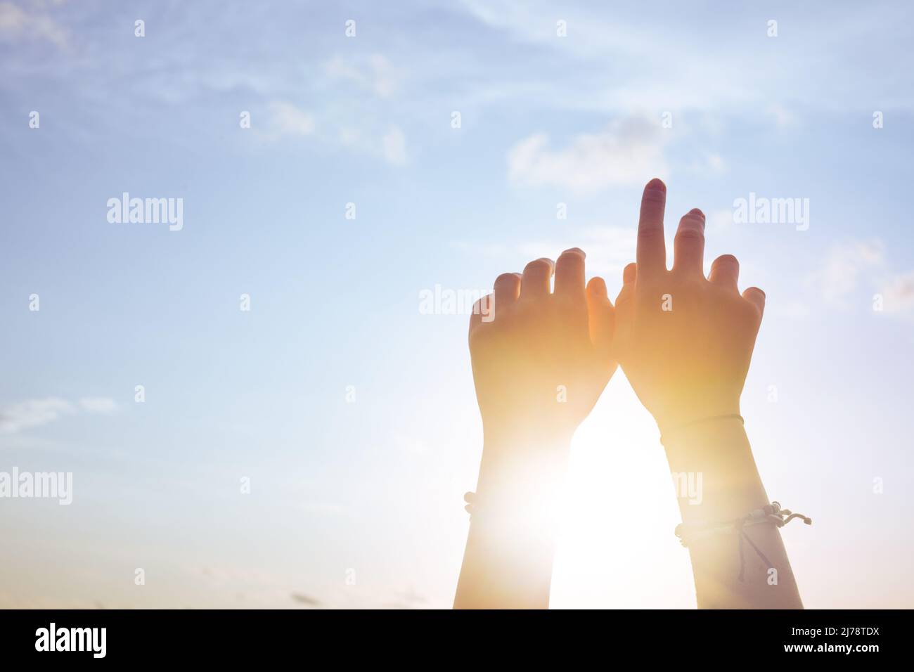 Le mani della donna contro il cielo blu e il sole Foto Stock