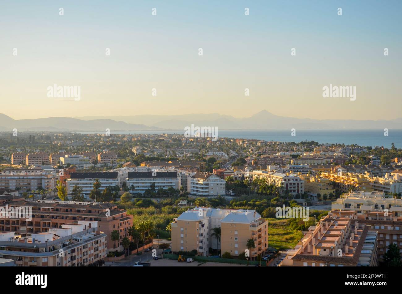 Vista dall'alto della città di Denia e tetti al tramonto. All'orizzonte si possono vedere l'oceano e le montagne sulla costa mediterranea Foto Stock