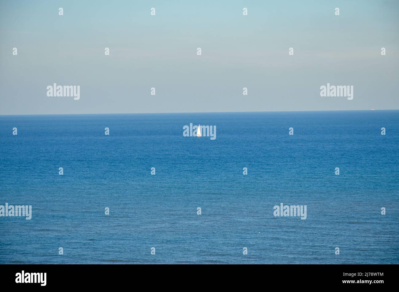 Una barca a vela solitaria all'orizzonte dell'oceano Mediterraneo Foto Stock