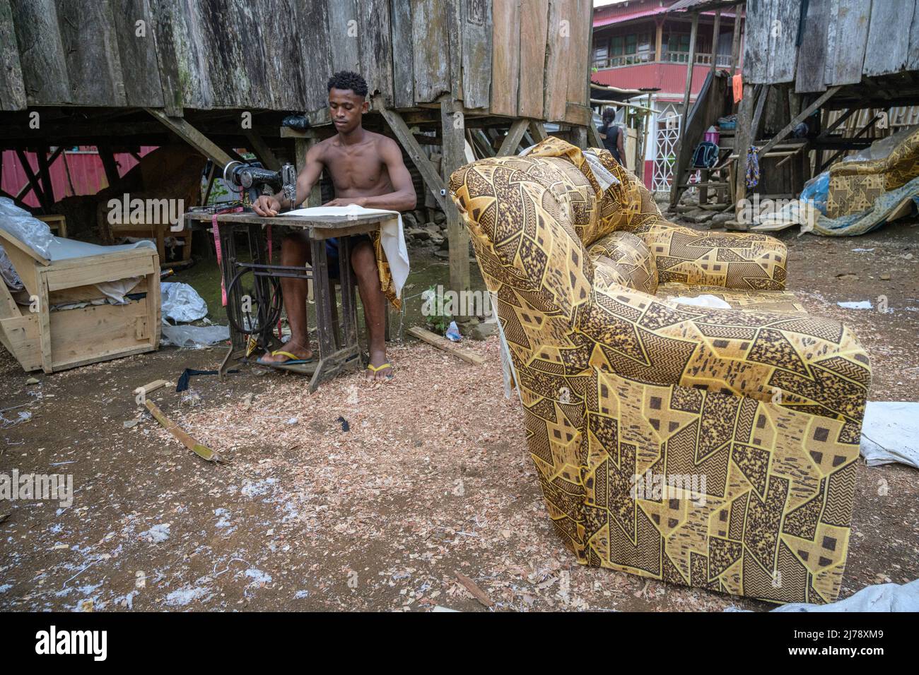 Giovane uomo che fa divani in una officina improvvisata accanto alla sua baracca di legno per le strade di Sao Joao dos Angolares. Foto Stock