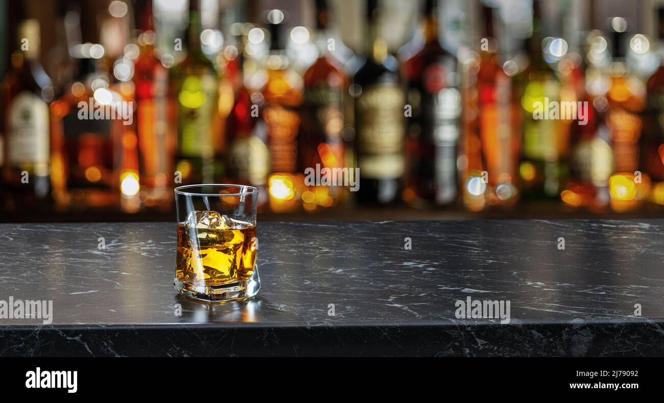 Bicchiere di whiskey sul bancone del bar. Interno sfocato della barra sullo sfondo. Foto Stock