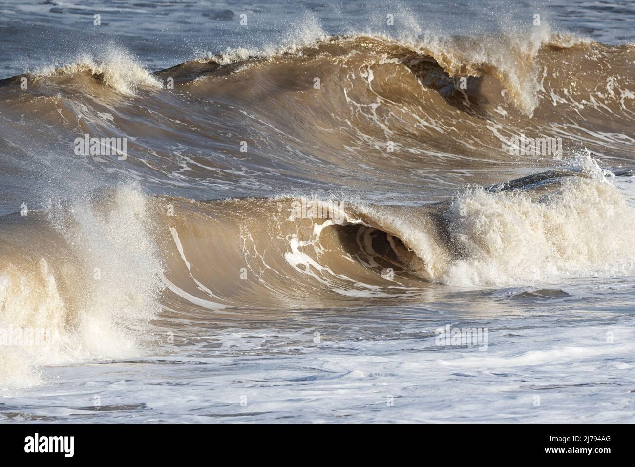 La cresta delle onde, la potenza e l'effetto astratto del fluido mare/acqua sulla costa di Norfolk, East Anglia, UK Foto Stock