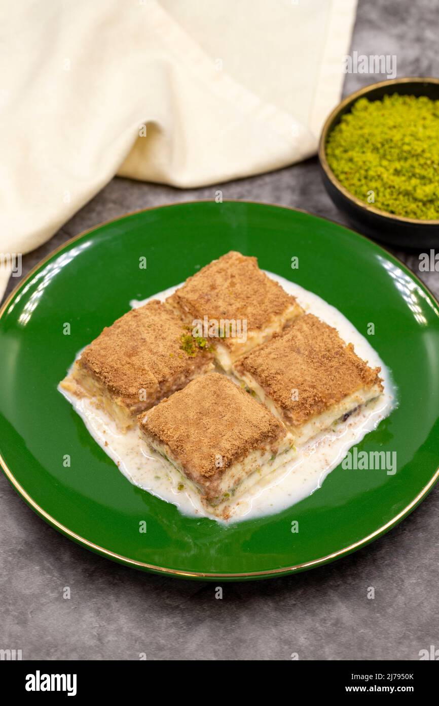 Baklava freddo. Baklava con latte su sfondo scuro. Prelibatezze della cucina mediterranea. Primo piano. Nome locale soguk baklava Foto Stock